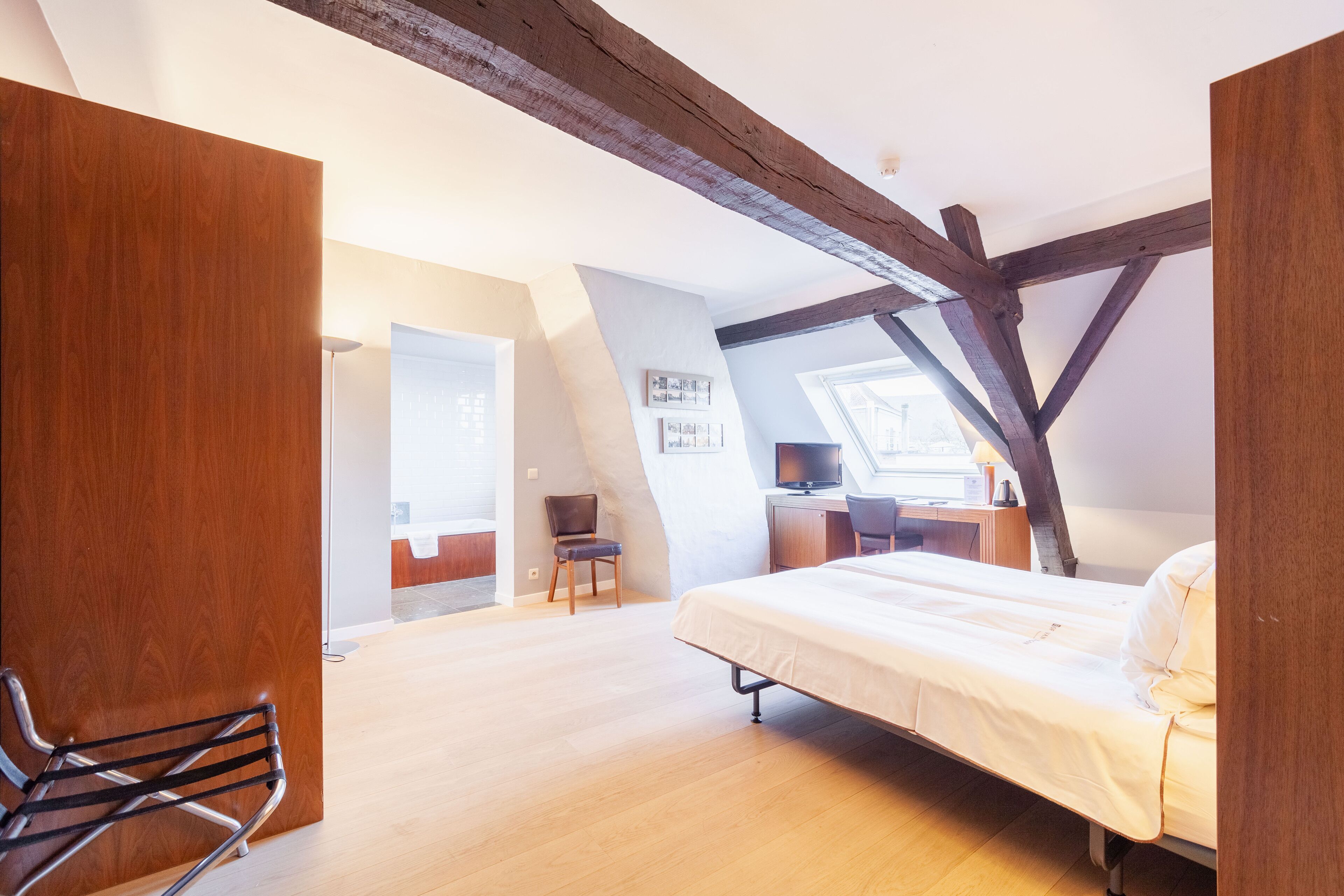 A bedroom with a bed, a desk, a chair, and a window.