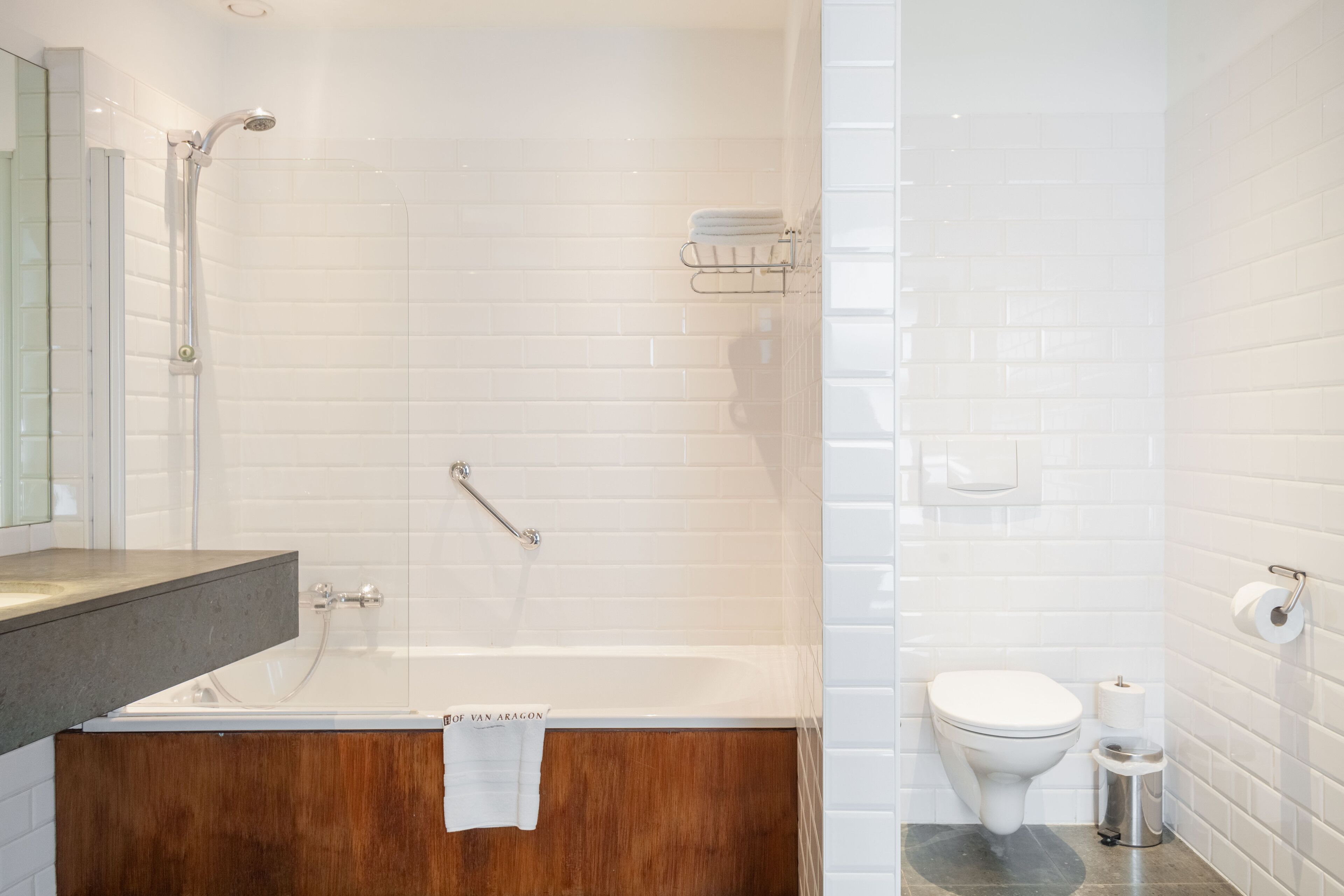 Un bagno moderno con una vasca, un mobile lavabo in legno, un WC e uno spazio doccia.