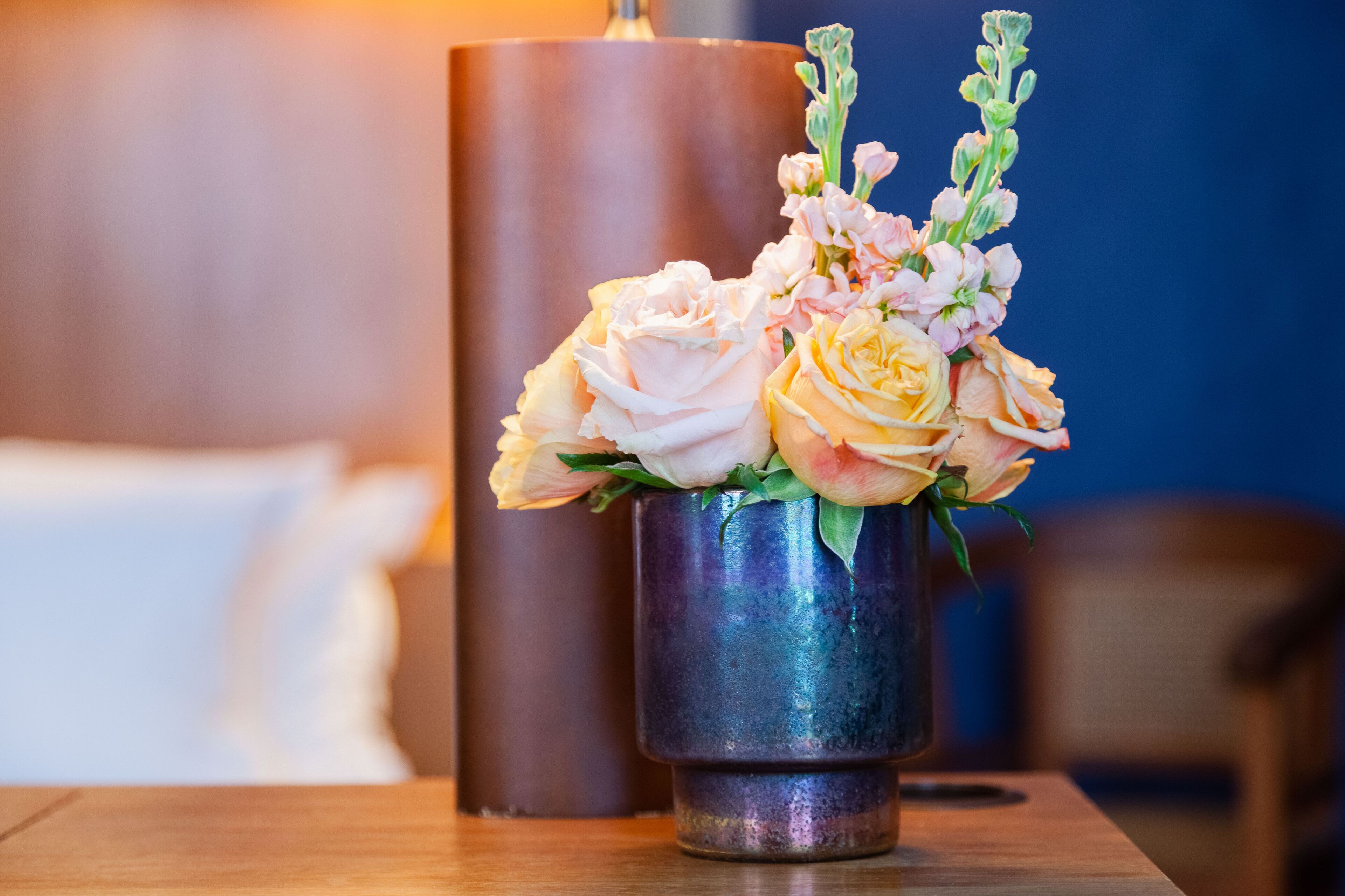 Un florero metálico con flores sobre una mesa de madera.