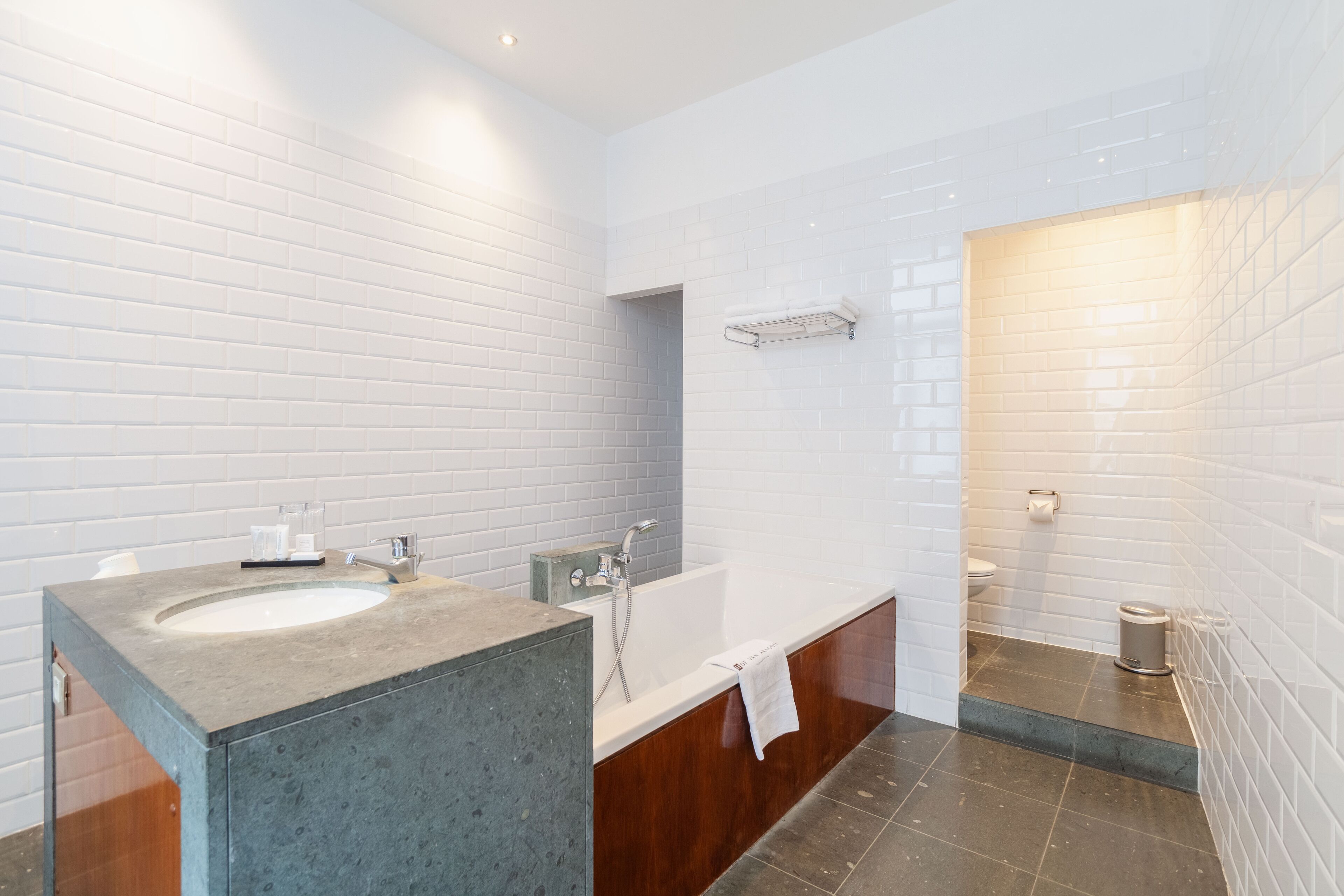 A modern bathroom with two sinks, a bathtub, and a toilet.