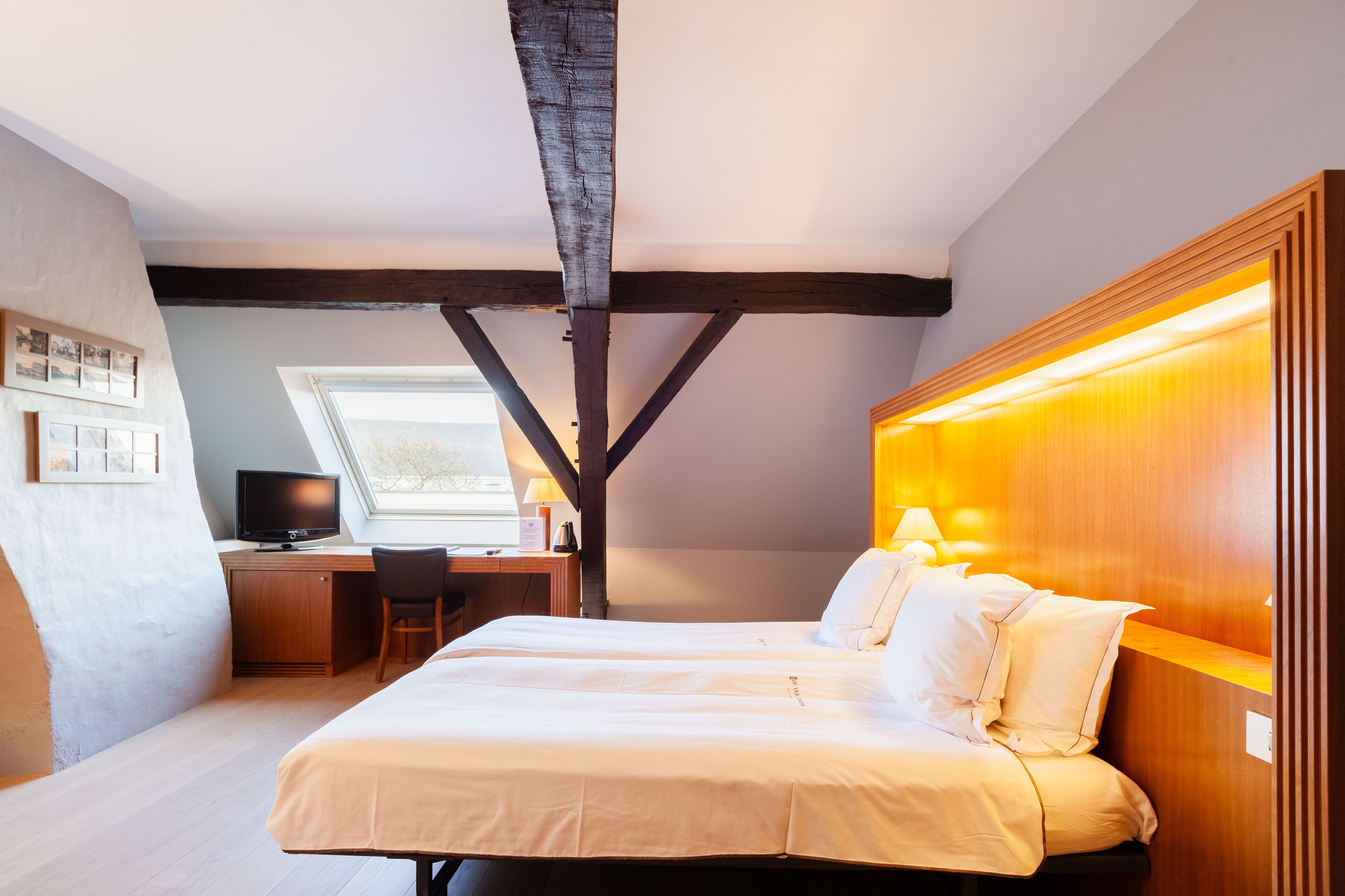 A bedroom with a bed, a desk, and a television.