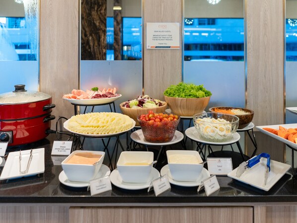 Un bufé con diversas opciones de comida y un letrero que indica que los alimentos del bufé de desayuno no pueden sacarse del restaurante.