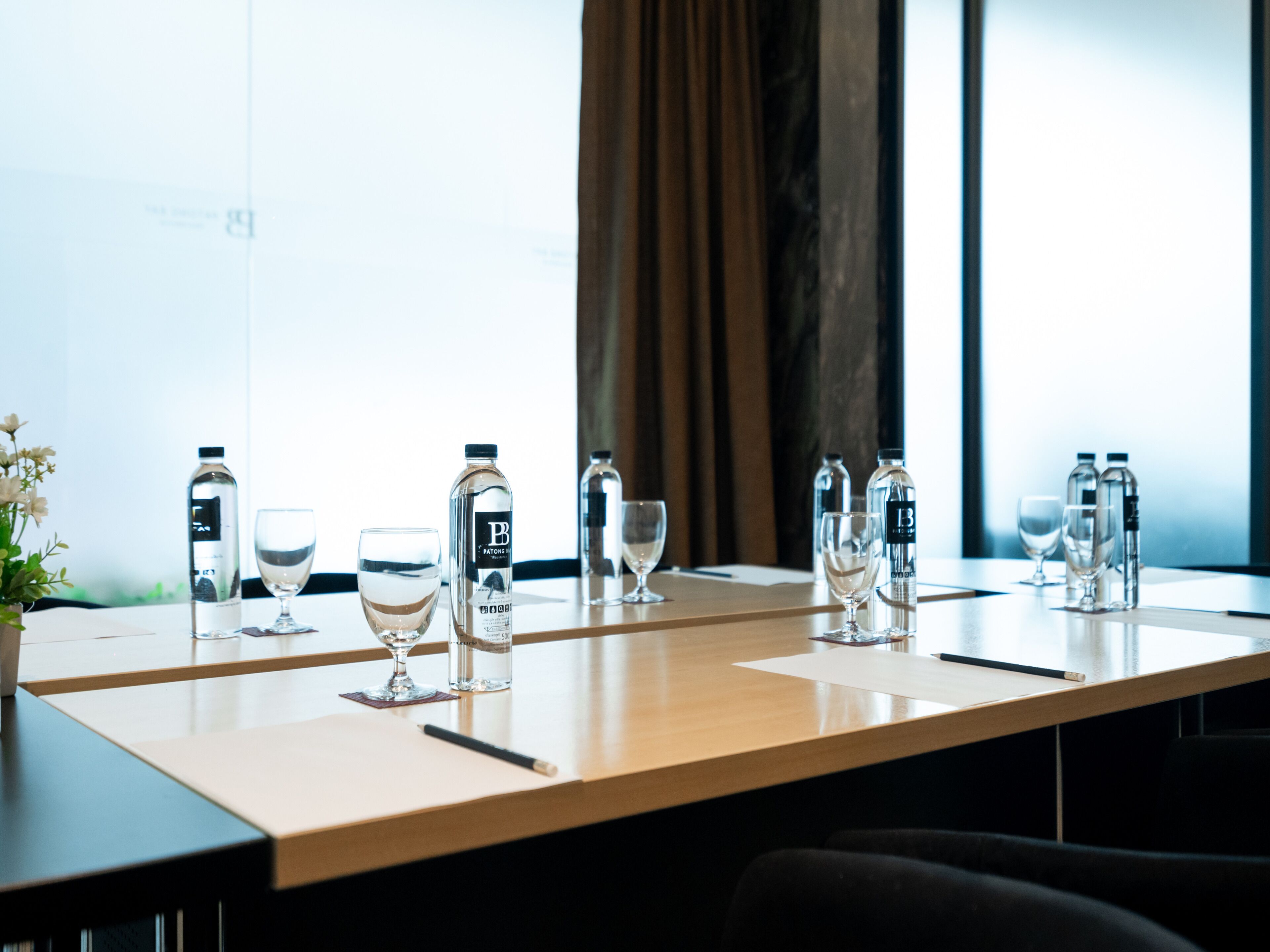 A conference table with water bottles, glasses, and a notebook.