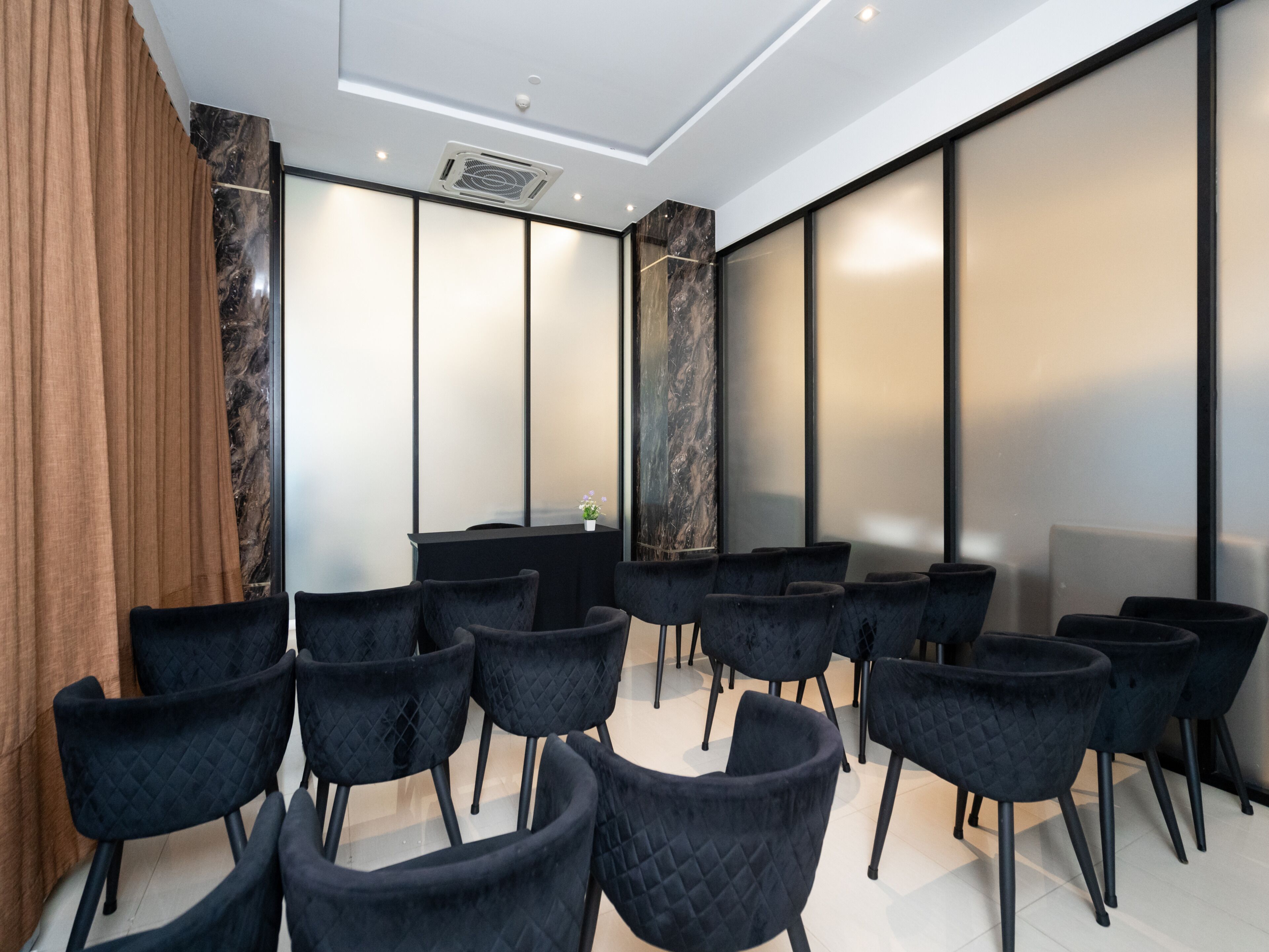A conference room with black chairs arranged in rows, a black table, and a large marble column.