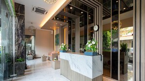 A modern reception area with a marble reception desk, seating area, and large windows offering views of the outside. - Patong Bay Residence  (Patong)