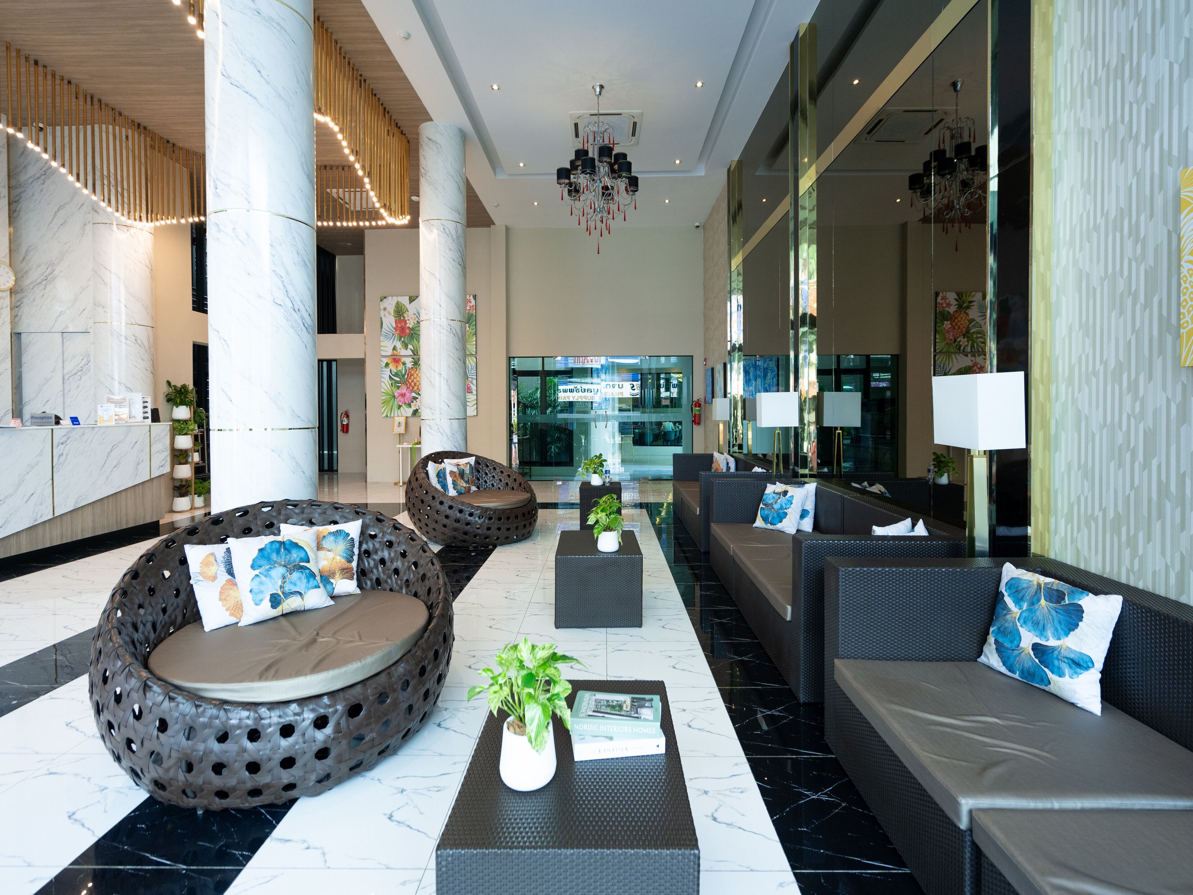 A modern lobby with seating areas, a reception desk, and a large mirror.