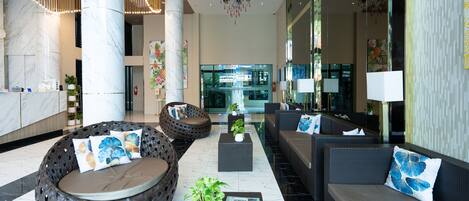 A modern lobby with seating areas, a reception desk, and a large mirror.