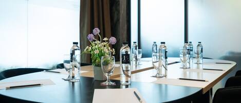 A conference table with water bottles, glasses, and a vase of flowers.