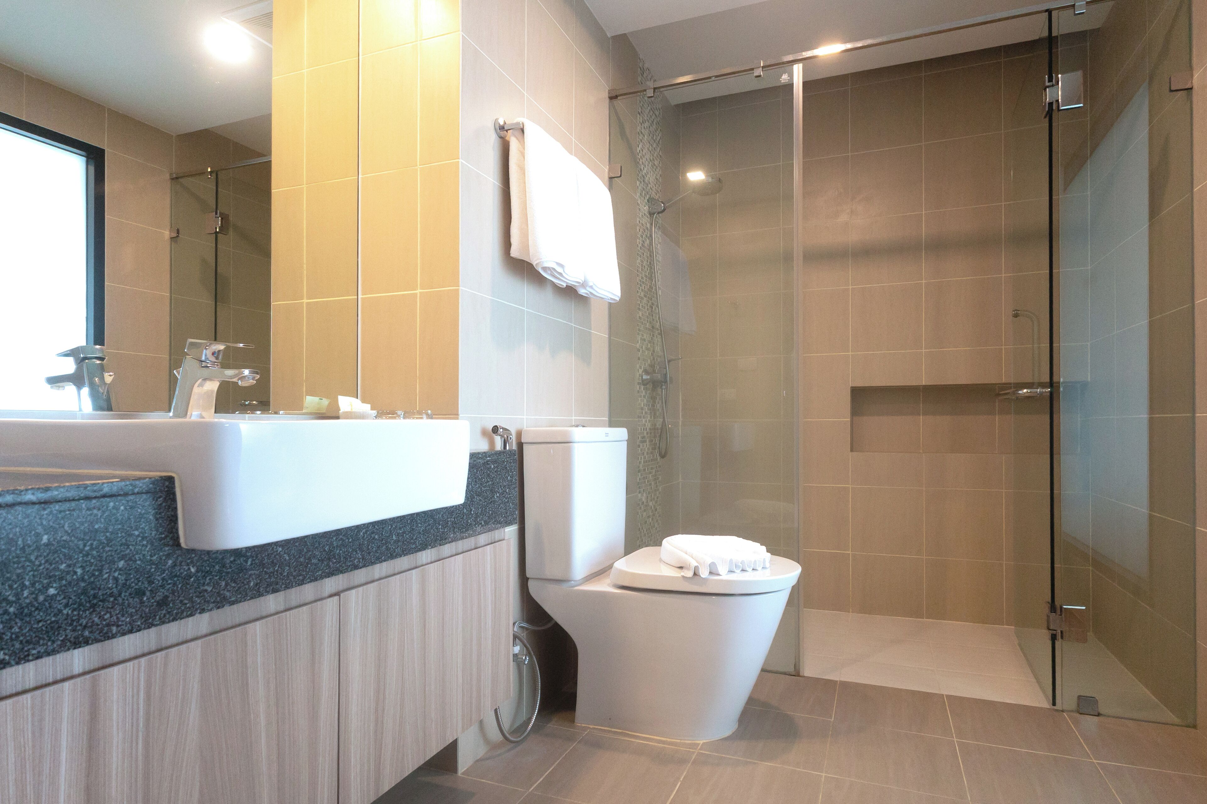 A modern bathroom with a sink, toilet, and glass shower enclosure.
