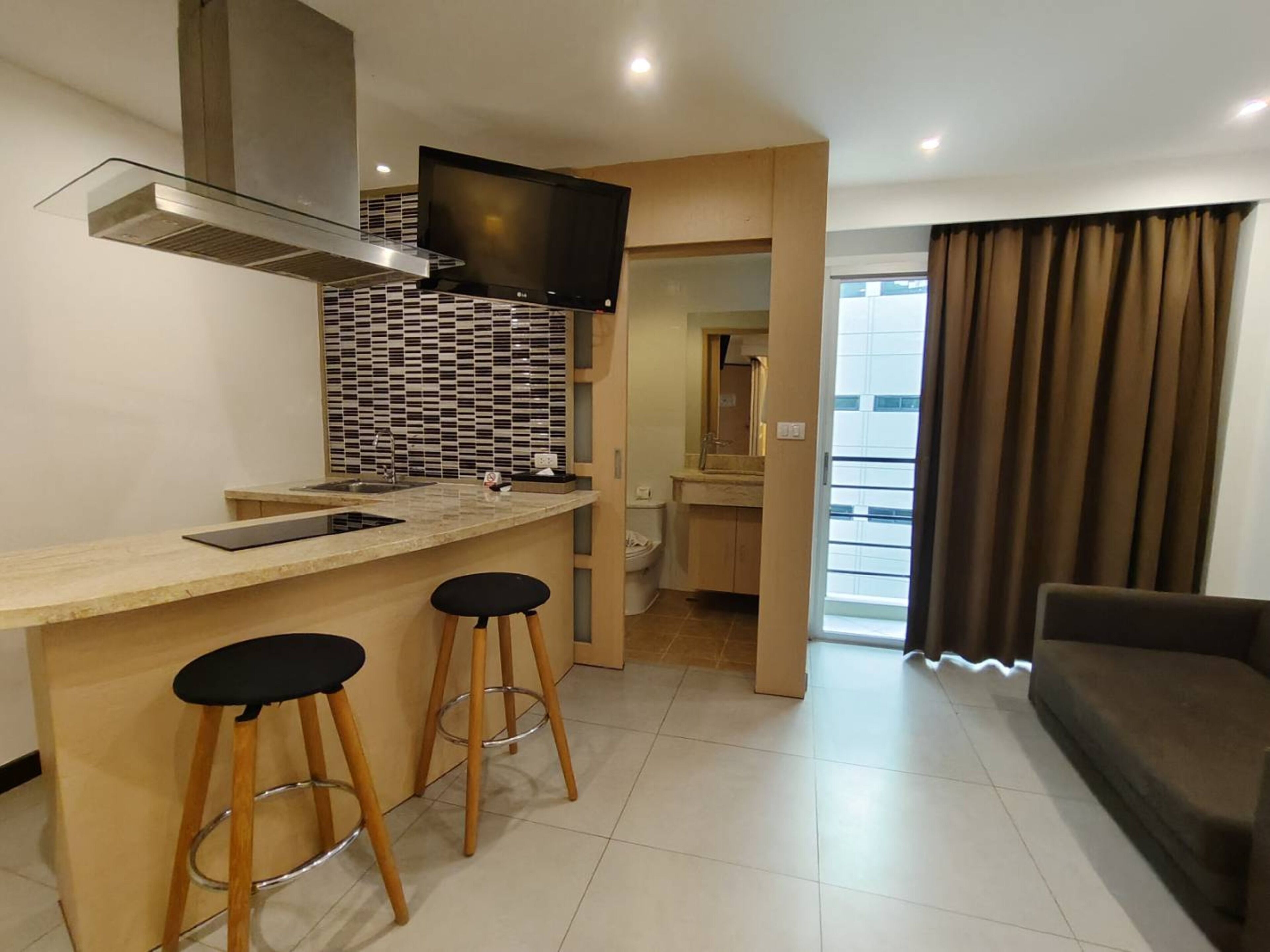 A modern kitchen with a TV, two stools, and a built-in oven.