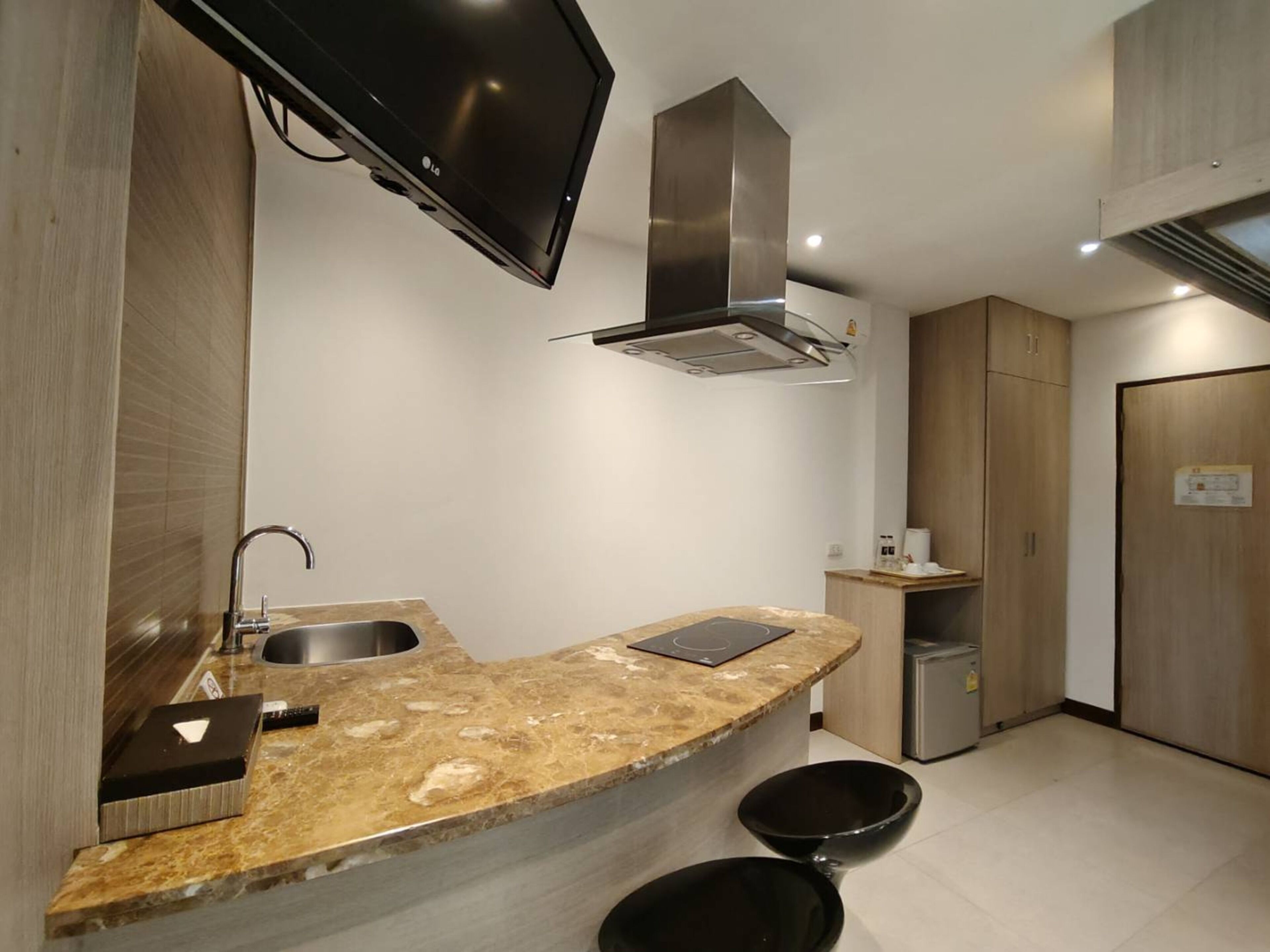 Una cocina moderna con encimera de granito curva, pileta de acero inoxidable y extractor de aire integrado.
