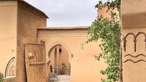 Un patio con un gran portón de madera, arcos y suelo de baldosas.