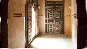 Un arco de entrada a una habitación con una puerta estampada y una lámpara colgante.