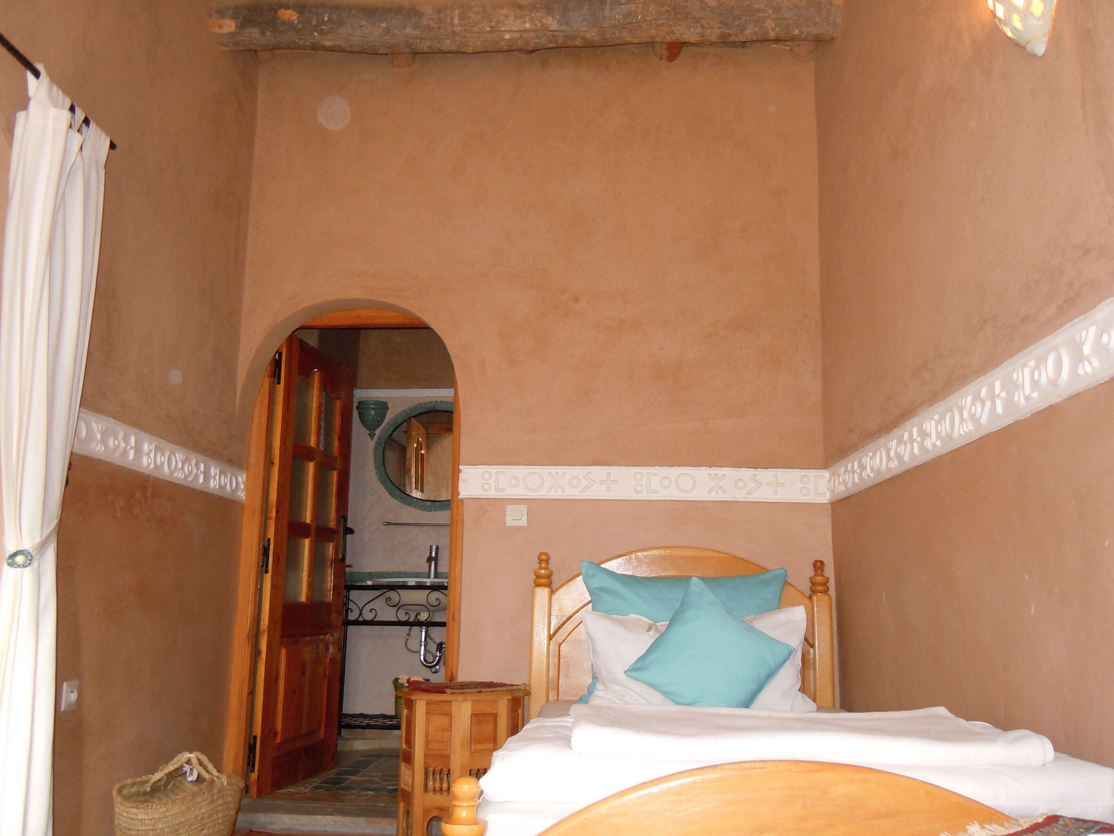 A bedroom with a wooden bed, a small bedside table, and a door leading to a bathroom.