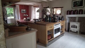 Een keuken met een houten kookeiland, witte kasten en een retro fornuis.