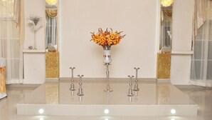 A room with a large mirror, a vase with flowers, and a decorative stand. - Millenium Manor Hotel (Georgetown)