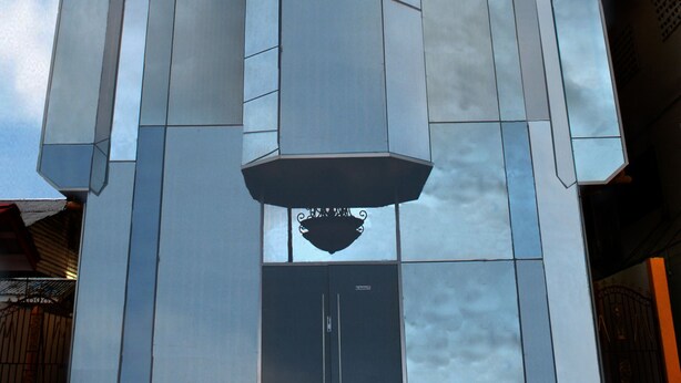 A modern building with a reflective glass facade and a central vertical element. - Millenium Manor Hotel (Georgetown)