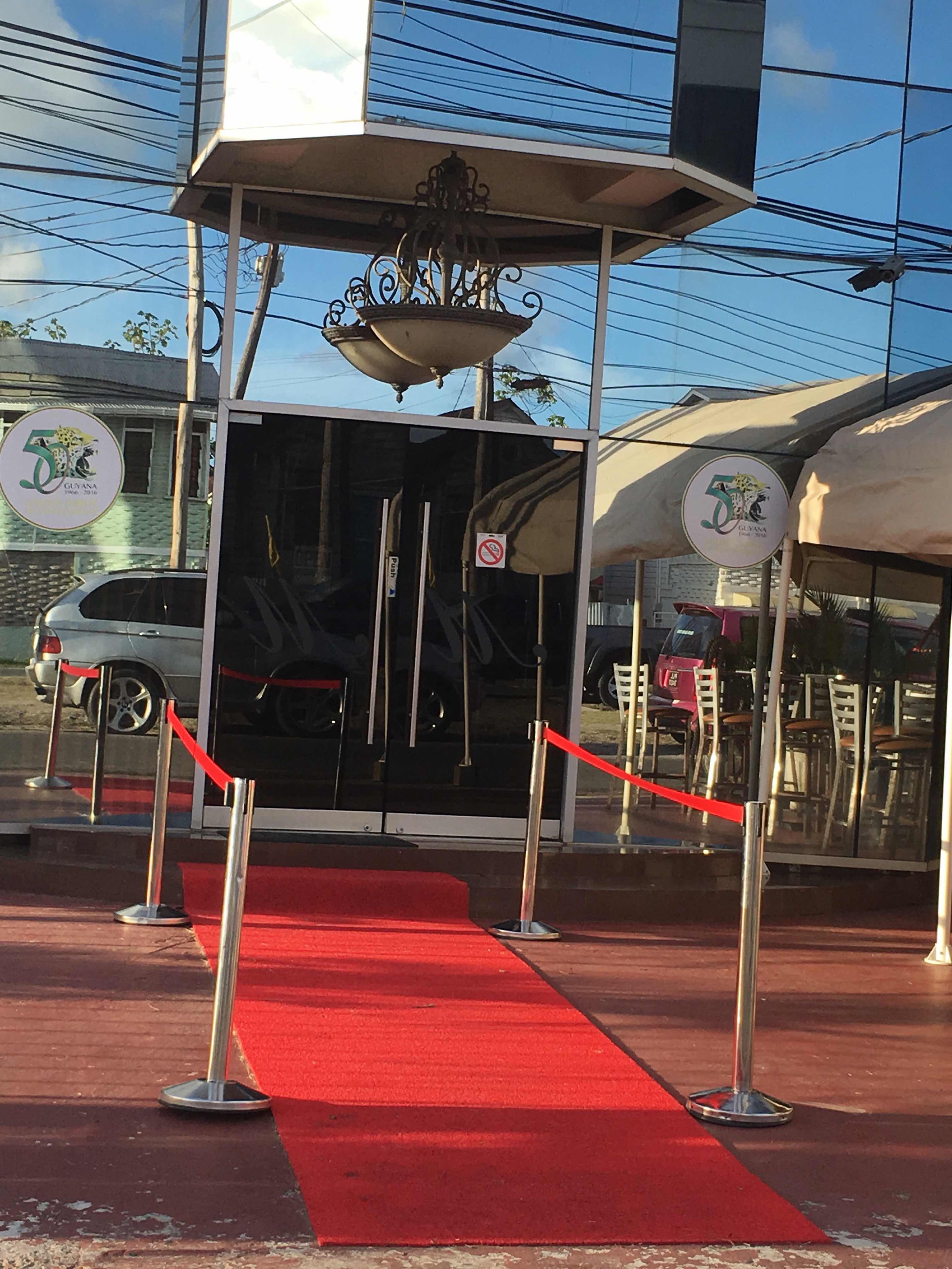 A building entrance with a red carpet, a no parking sign, and a logo with a lion and the number 5.