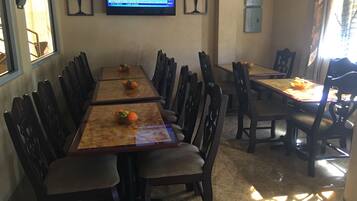 Un comedor con una mesa larga y sillas, un televisor montado en la pared y apliques decorativos.