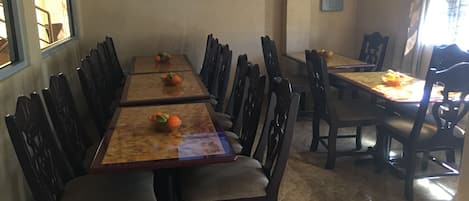 Un espace repas comprenant une longue table et des chaises, un téléviseur fixé au mur et des appliques murales décoratives.