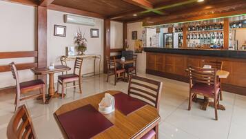 A restaurant with wooden furniture, a bar area with bottles, and a clean tiled floor.