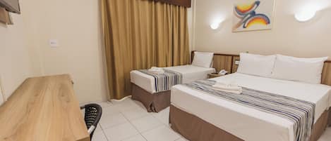 A hotel room with two beds, a desk, a chair, a bathroom, and a painting on the wall.