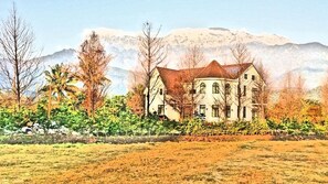A large, two-story building with a symmetrical facade, surrounded by a well-maintained garden and trees. - Gihak Homestay (Shoufeng)