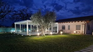 A modern house with a glass conservatory, a well-maintained lawn, and a stone pathway leading to the entrance. - Il Rifugio Del Tempo (Roccasecca)