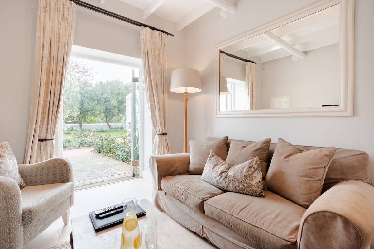 A living room with a beige sofa, a coffee table with a remote control, and a lamp.