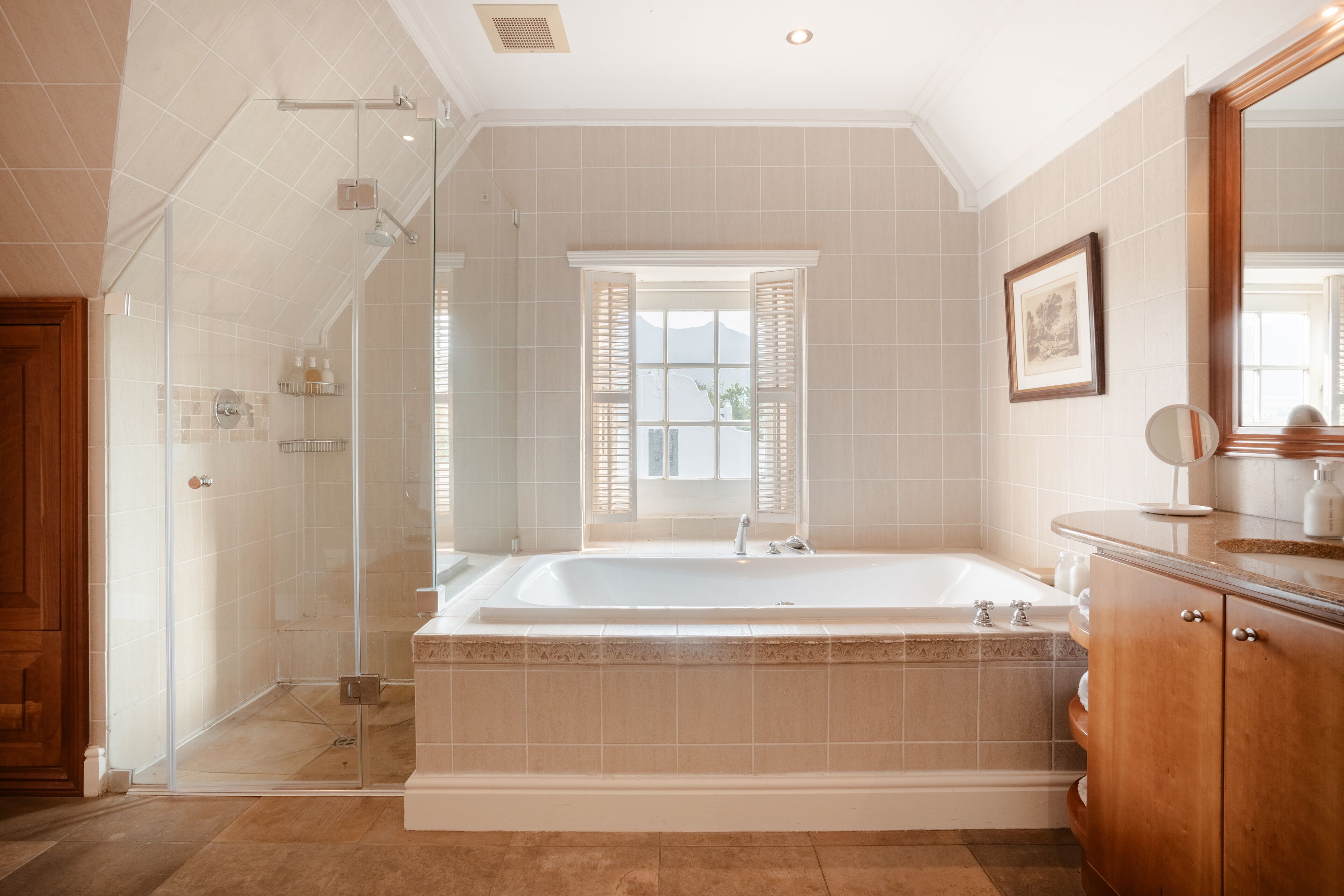 Un baño moderno con una bañera grande, una cabina de ducha de vidrio y una ventana con contraventanas.