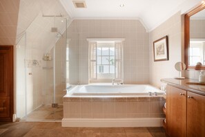 A modern bathroom with a large bathtub, a glass shower enclosure, and a window with shutters. - Vrede en Lust Wine Estate (Paarl)