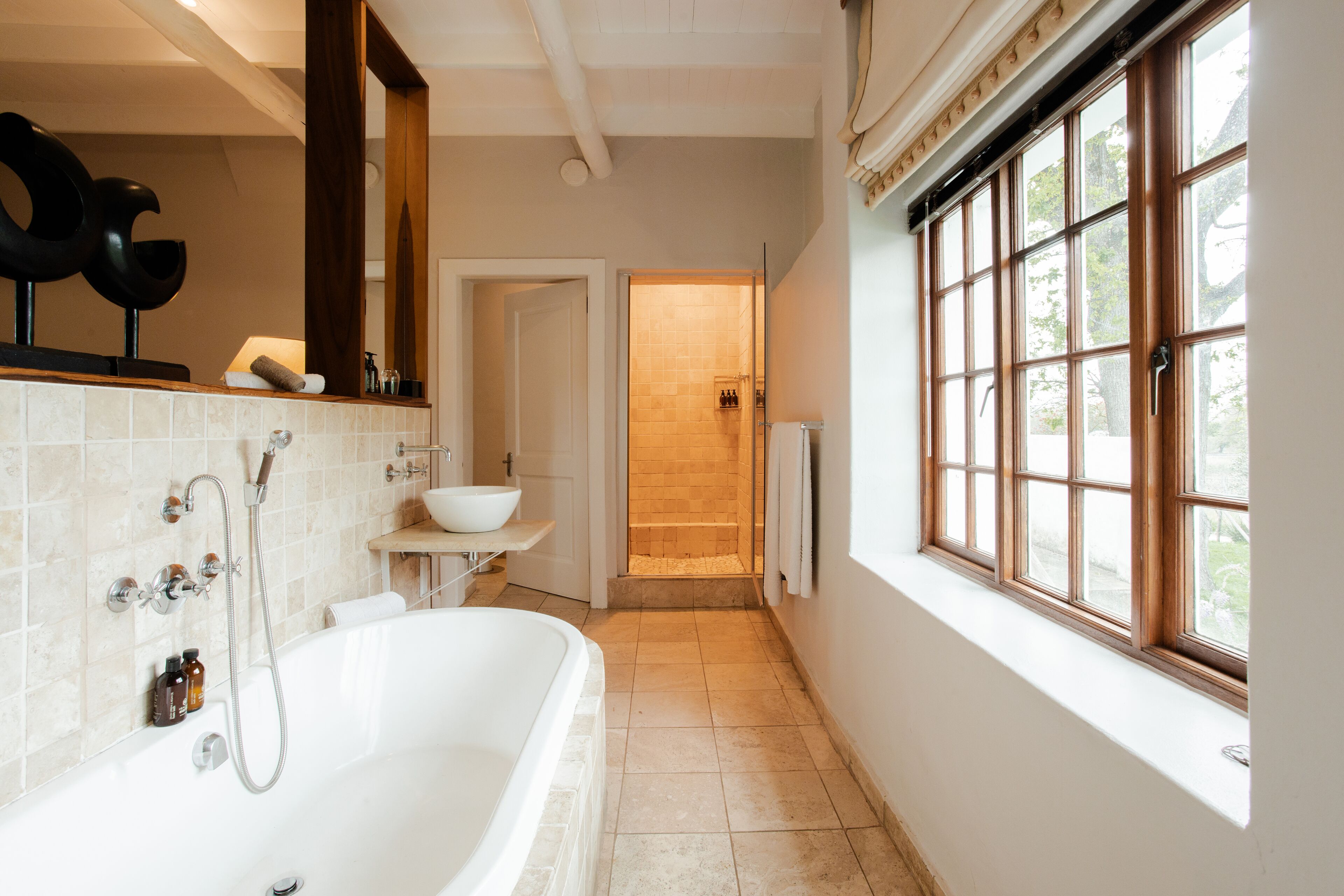Une salle de bain moderne avec une baignoire sur pieds, une grande fenêtre et une douche à l’italienne.