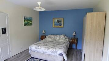 Ein Schlafzimmer mit einem Bett, zwei Nachttischen, einem Deckenventilator, einem gerahmten Bild und einer Tür.