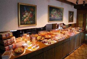 Buffet com diversos alimentos e uma pintura de flores na parede.