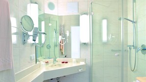 Un baño moderno con cabina de ducha de vidrio, lavamanos con espejo y toallero.