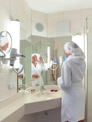 Un baño moderno con un espejo grande, un secador de pelo y un lavabo.