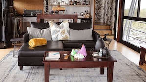 Ein modernes Wohnzimmer mit Sofa, Couchtisch und einer Küche im Hintergrund.