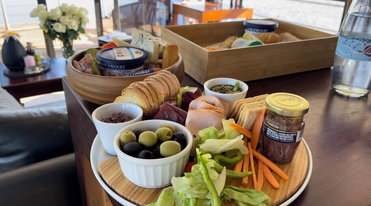 A table with a variety of food items including bread, meats, olives, and vegetables.