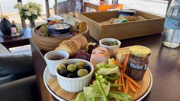 A table with a variety of food items including bread, meats, olives, and vegetables.