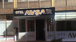 Ett hotell som heter ”OTEL AVSAR”, med en framträdande skylt, en entré med röd matta och ett stort fönster med gardiner.