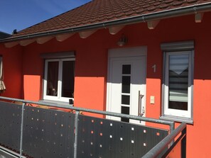 A red building with a white door, two windows, and a balcony railing. - Gästehaus Durst (Rust)