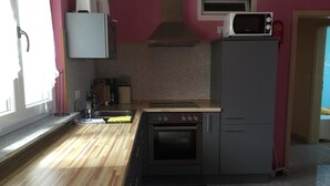 A compact kitchen with a wooden countertop, a built-in oven, a microwave, and a sink. - Gästehaus Durst (Rust)