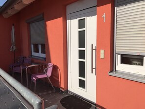 Un petit espace extérieur aménagé avec une table et des chaises, une porte avec une fenêtre et une porte-fenêtre coulissante.