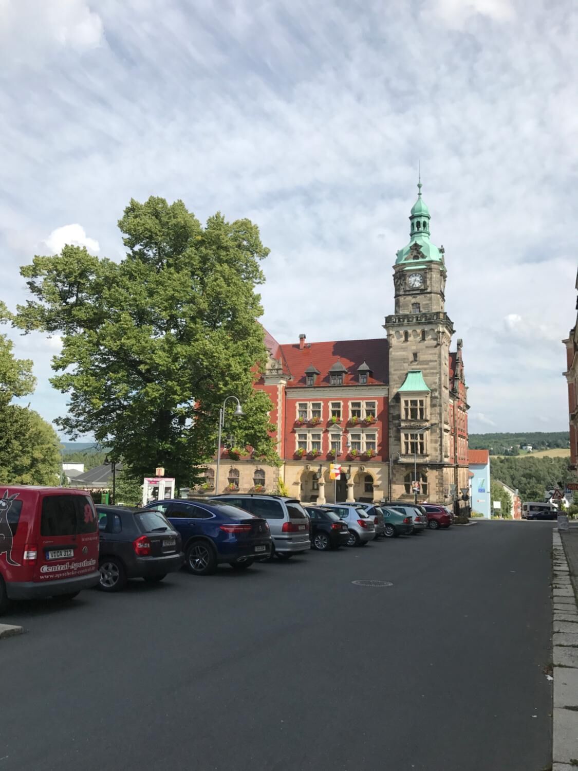A street with parked cars and a historic building with a clock tower.