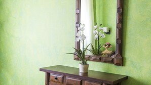Un meuble-lavabo de salle de bain avec un miroir, une orchidée en pot et une petite statue.