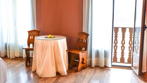 Une pièce avec une table ronde recouverte d’une nappe blanche, deux chaises en bois et un plancher en bois.
