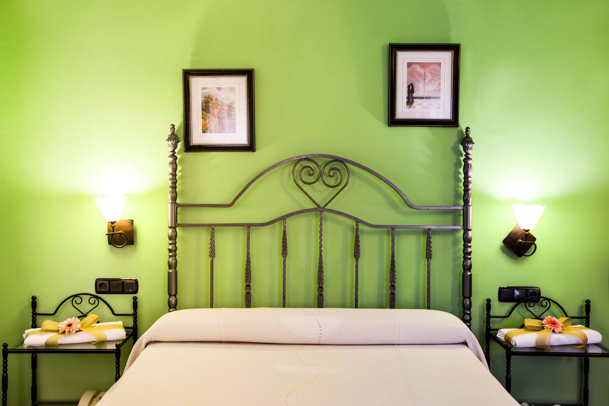 A bed with a headboard, two nightstands with lamps, and two framed pictures on the wall.