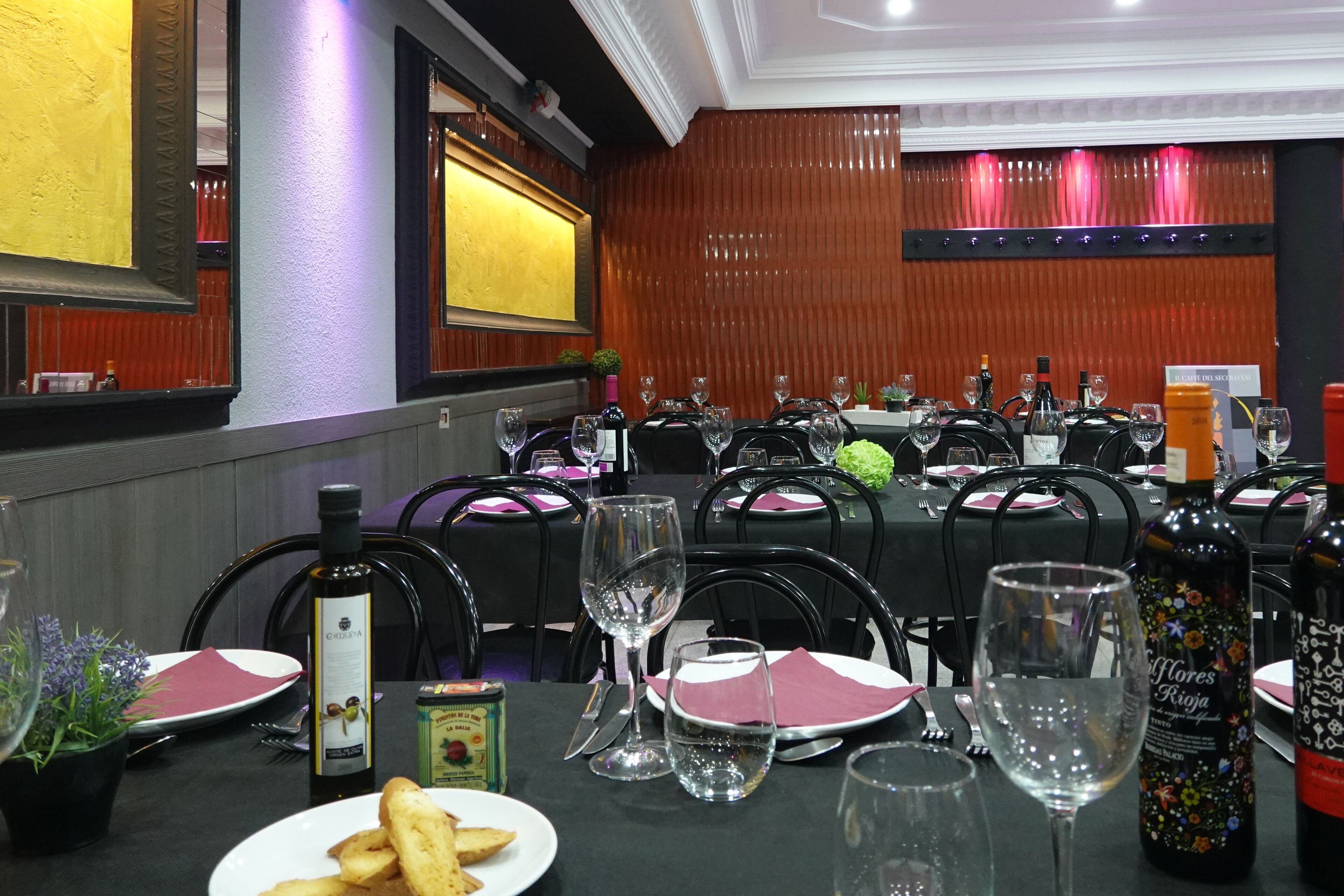 A dining area with multiple tables set for guests, each with wine glasses, plates, and cutlery.