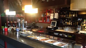 Un espace buffet proposant divers plats, une caisse enregistreuse et un bar avec des bouteilles et des verres.