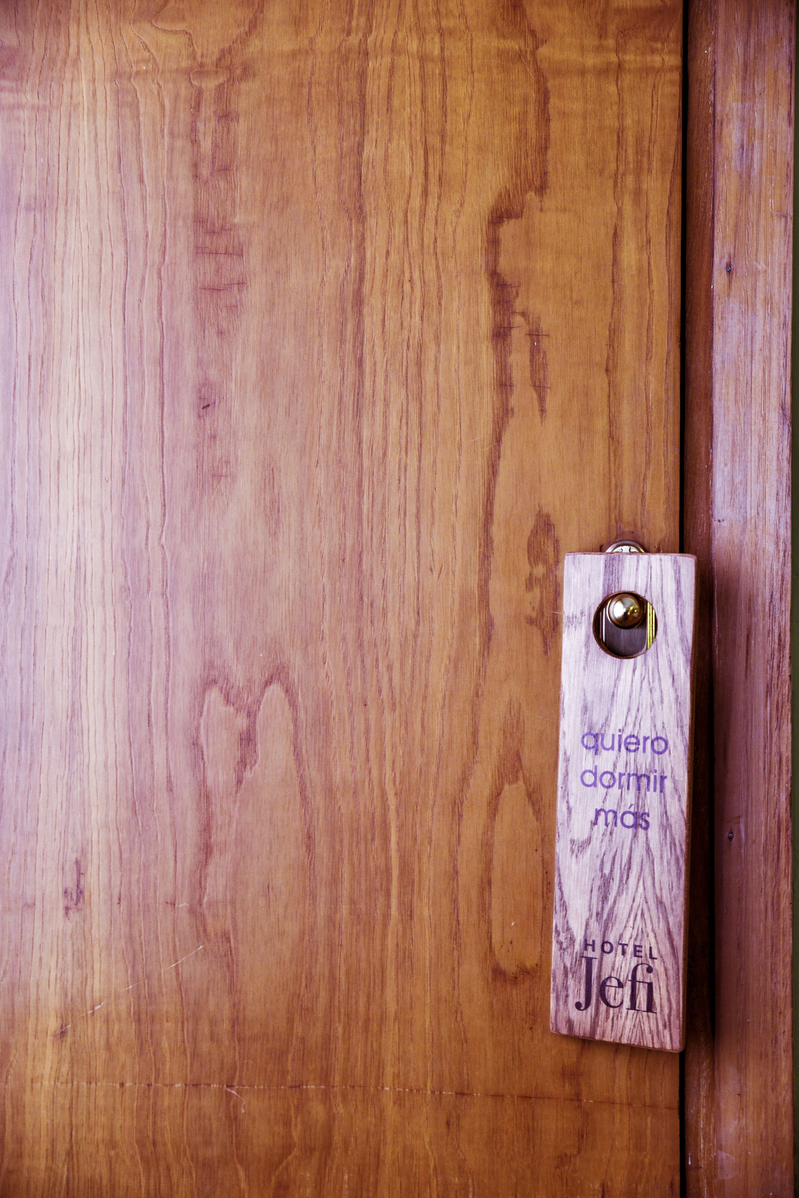 Una porta in legno con maniglia metallica e una targa in legno con la scritta "quiero dormir mas HOTEL Jef".